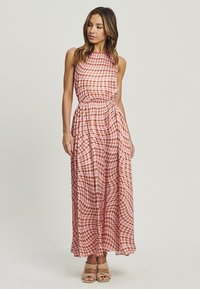Abito lungo con scollatura alta, caratterizzato da un motivo a scacchi rosa e rosso. Tessuto leggero, vita arricciata e gonna fluente.
