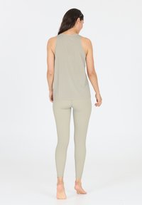 Canotta grigia chiaro e leggings in un tessuto morbido e stretch. La canotta ha un neckline arrotondato e i leggings si adattano perfettamente alle caviglie.
