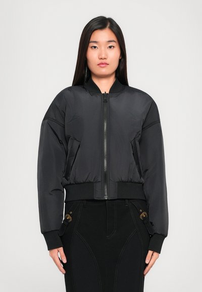 Veste bomber noire avec fermeture éclair sur le devant, poignets et ourlet côtelés, dotée d'un design matelassé et de poches latérales pour plus de fonctionnalité.