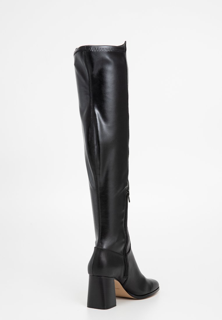 Stivale in pelle nera al ginocchio con tacco a blocco, cerniera laterale, texture liscia e design aderente.