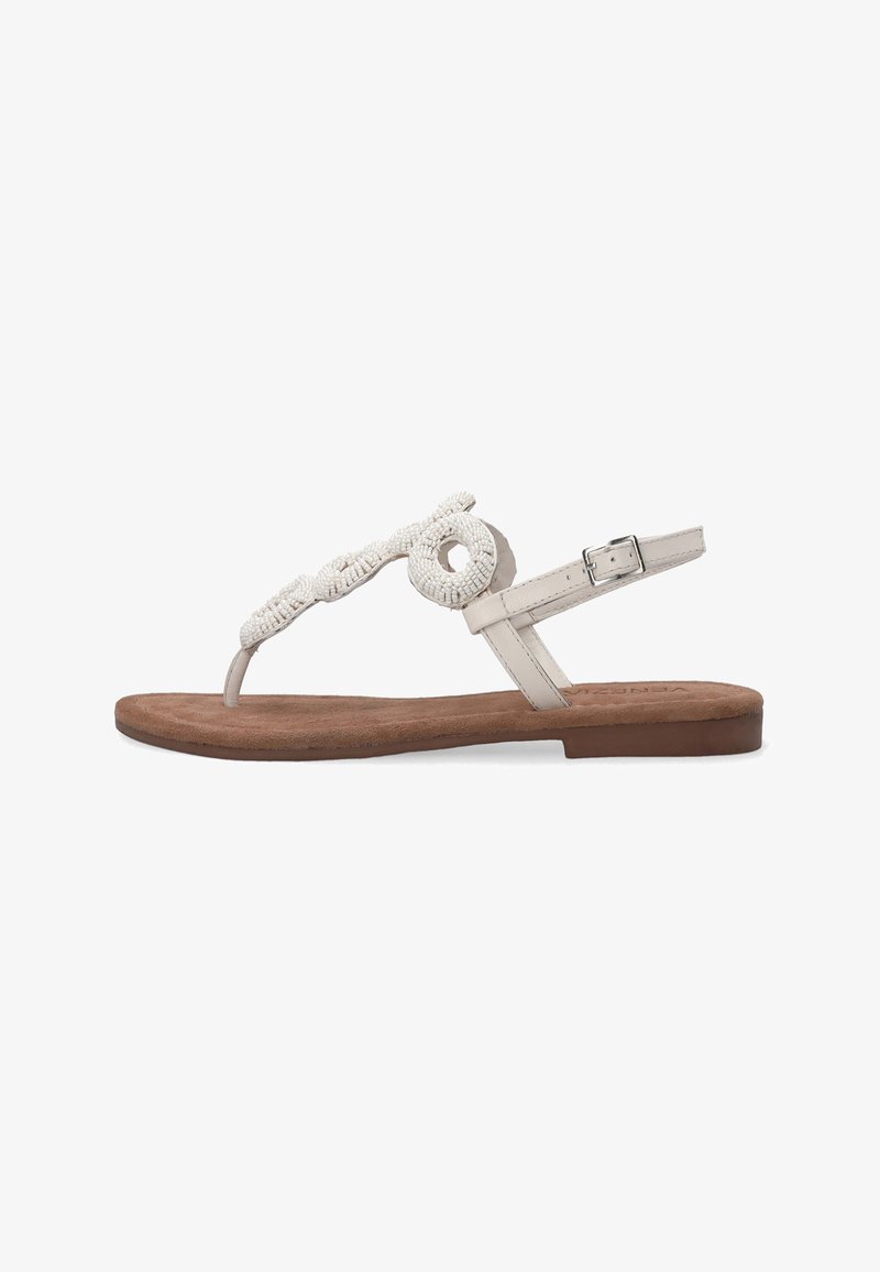 Beige tanga sandal med en tekstureret overdel, der har cirkulære perleaccentuer, flad brun sål og en justerbar ankelrem.