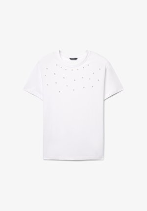 T-shirt bianca a maniche corte con decorazioni sparse di perle finte e cristalli sul davanti. Classico scollo rotondo, morbido tessuto in cotone.