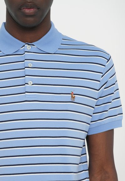 Ανοιχτό μπλε πόλο μπλουζάκι με ναυτικές και λευκές οριζόντιες ρίγες, κοντά μανίκια, μπροστινό κούμπωμα με τρία κουμπιά, και ένα μικρό κεντημένο λογότυπο στο στήθος.