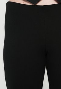 Mustad retuusid, valmistatud sileda ja veniva kangaga. Omavad laia vöökohaga ja tiheda istuvusega vööst ääreni. Ilma nähtavate mustrite või detailideta.