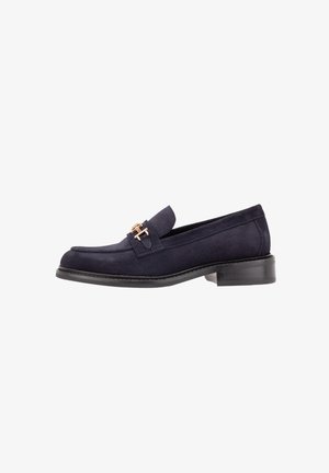 Mocassin en daim bleu marine avec un petit talon et un détail boucle en métal doré à l'avant, présenté de profil.