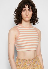 Top cropped às riscas em cores pêssego suave e creme, feito de tecido canelado com decote redondo e design sem mangas.