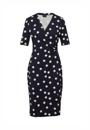 Marineblauwe jurk tot op de knie met witte polka dots, korte mouwen, V-hals en geplooide details aan de rechterkant van de taille.