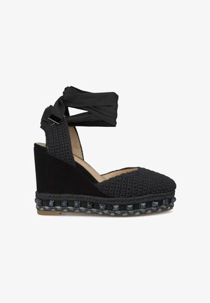 Espadrille nera con zeppa e parte superiore in tessuto lavorato, caratterizzata da una finitura texturizzata, cinturini in tessuto regolabili e suola in juta intrecciata.
