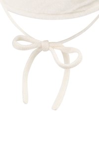 White fabric hat with a round top and a fixed bow tie closure. The tie is made of woven material, giving a soft texture.