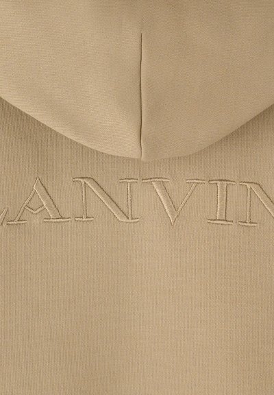 Beige Kapuzenpullover mit glatter Textur, verziert mit gesticktem "LANVIN" in einem etwas dunkleren Beige. Kapuze und Nahtdetails sind oben sichtbar.