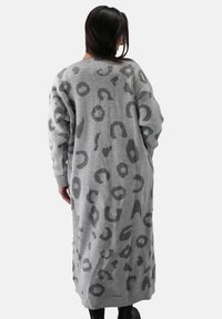 Lang grå sweater med leopardprintmønster i mørkere grå, med oversized ærmer og ribbede manchetter. Blødt, struktureret strikmateriale.
