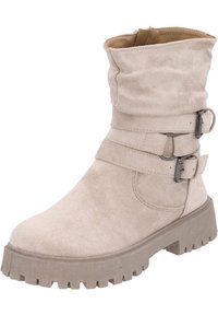 Bottine en daim beige avec un dessus replié, deux sangles ajustables et des éléments en métal argenté. Semelle épaisse et crantée pour une bonne adhérence.