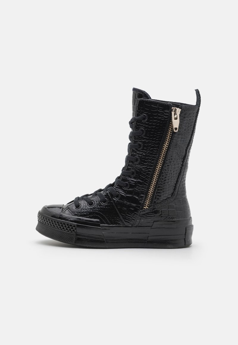 Bottine sneaker noire montante avec surface texturée, lacets à l’avant, semelle en caoutchouc et fermeture éclair latérale sur fond blanc.