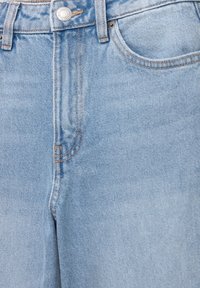 Jeans en denim bleu clair avec taille haute, coutures orange contrastantes et fermeture à bouton en argent. Comprend des poches avant et un design à jambe droite.