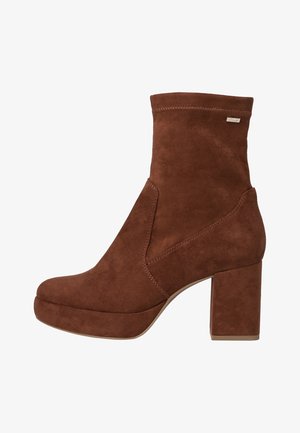 Stivali alla caviglia in suede marrone con tacco chunky, caratterizzati da una texture liscia, ritagli laterali e design minimalista.