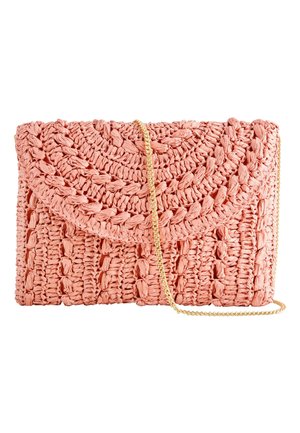 Lyserød vævet clutch-pung med en rundet flap og en tynd guldkæde på hvid baggrund.