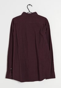 Camicia bordeaux a maniche lunghe con colletto button-down, caratterizzata da un orlo dritto e polsini con bottone. Texture liscia e design semplice.