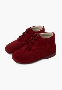Zapatos de ante rojo con cordones, punta redonda, detalles con ondas y pequeños cortes, que presentan un forro interno suave y suela plana.