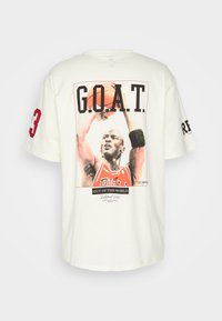 Kremowy bawełniany t-shirt z dużym nadrukiem graficznym koszykarza, na którym znajduje się napis "G.O.A.T." oraz numer 23, krótki rękaw.