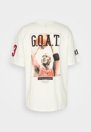 Kermanvärinen puuvillainen t-paita, jossa on suuri graafinen printti koripalloilijasta tekstillä "G.O.A.T." ja numero 23, lyhyet hihat.