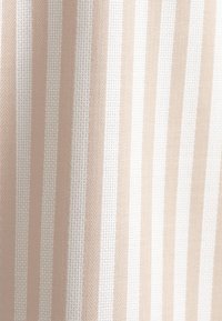 Tessuto a righe con linee alternate di beige chiaro e bianco, caratterizzato da una tessitura testurizzata e un sottile motivo a spina di pesce.