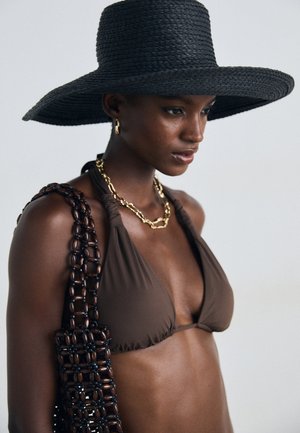 Brown bikini top with triangular cups, paired with a textured black wide-brim hat and a dark patterned bag featuring chain accents.