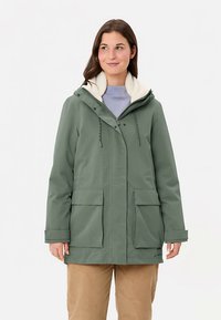 Olijfgroene buitenkant jas met een pluizige witte voering, verstelbare capuchon met trekkoord, en twee voorzakken. Eenvoudig, praktisch ontwerp.