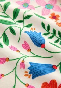 Tessuto floreale con fiori blu, rosa e arancioni collegati da steli e foglie verdi su uno sfondo bianco.