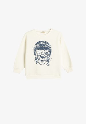 Sudadera color crema hecha de una tela suave que presenta un gráfico azul de un tigre con un casco y el texto "AHORA ES EL MOMENTO SALVAJE, MONTA PARA NACER."