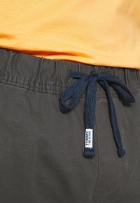 Donkergrijze shorts met een elastische tailleband en een marineblauwe trekkoord. Voorzien van een klein 'Tommy Jeans' logo-tag aan de zijkant.
