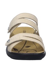 Beige sandaal met twee brede banden en zilverkleurige hardware. Gecorrodeerde voetbed met een bladontwerp, zwarte loopzool voor grip.