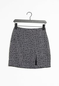 Jupe à motifs black and white avec une taille élastique et une fente sur le devant, fabriquée en tissu léger, suspendue sur un cintre noir.