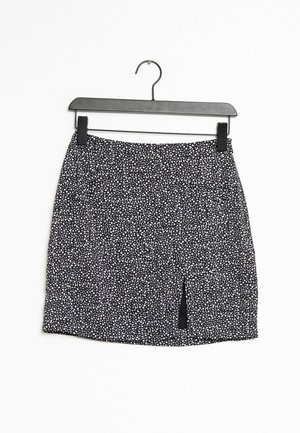 Jupe à motifs black and white avec une taille élastique et une fente sur le devant, fabriquée en tissu léger, suspendue sur un cintre noir.