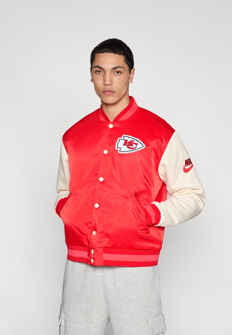 Rotes Satin-Collegejacke mit cremefarbenen Ärmeln, auf der ein KC-Logo und Nike-Branding zu sehen sind. Gerippter Kragen und Bündchen, Druckknopfverschluss und Taschen.