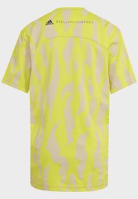 Gul kortärmad skjorta med ett beige abstrakt mönster. Inkluderar Adidas och Stella McCartney-logotyp på övre delen av ryggen.