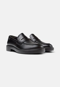 Black leather slip-on loafers with penny strap detail, rounded toe, and ridged sole, shown against a white background.