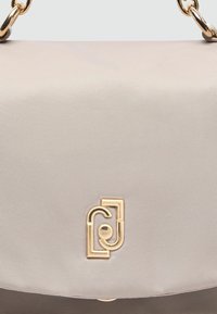 Sac à main synthétique texturé beige avec quincaillerie logo en ton doré et bandoulière en chaîne, doté d'une fermeture à rabat lisse.