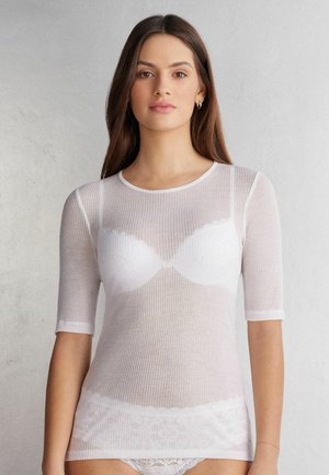 Top bianco a maniche corte con scollo rotondo, in tessuto leggero e traslucido, con pizzo ondulato decorativo all'orlo.