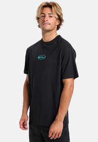 Camiseta de algodón negra de manga corta, con un logo turquesa en el pecho y un corte recto. Textura lisa, sin patrones ni acentos.