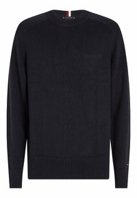 Pull en maille bleu marine avec col rond, poignets et ourlet côtelés, arborant un logo discret en relief sur la poitrine et un détail rayé au niveau du col.