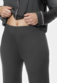 Grijze loungebroeken van zachte stof, met een elastische tailleband en een gladde textuur, gecombineerd met een bijpassend top met lichte accenten.