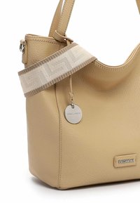 Beige leather handbag with a textured finish, featuring a wide patterned strap and a metallic charm. Prominent brand logo on the bag.