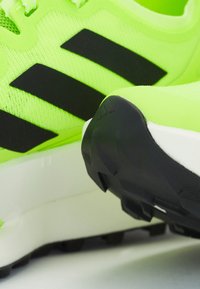 Svijetlo neon zelene atletske tenisice s crnim prugama, gornji dio od teksturiranog mrežastog materijala i gumeni potplat s uzorkom na gaznom sloju.