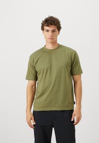 Olivegrünes T-Shirt mit kurzen Ärmeln aus weichem Stoff, mit Rundhalsausschnitt und lässiger Passform. Minimalistisches Design ohne sichtbare Muster oder Akzente.