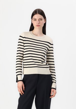 Cremfarbener Pullover mit schwarzen horizontalen Streifen, rundem Ausschnitt, langen Ärmeln, gerippten Bündchen und Seitenschlitzen am Saum. Getragen mit schwarzen Hosen.