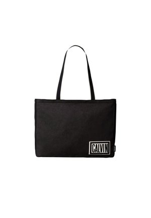 Sort rektangulær shopper med to tynde håndtag og et hvidt mærkat med teksten "CALVIN" i nederste højre hjørne.