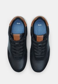 Mustad mustreejal saapad, mille ülemine osa on valmistatud siledast nahast ja sametist, pruuni aktsendiga, tekstuuriga sinised sisetallad ja mustad paelad. Kummist tallad.