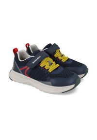 Zapatillas deportivas azul marino con parte superior de malla, cordones amarillos, acentos rojos y correa de velcro. Presentan una suela blanca acolchada.