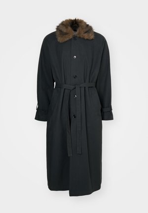 Langer schwarzer Mantel mit einem Fellkragen, Knopfverschluss vorne, tailliertem Gürtel und umgekrempelten Ärmeln. Aus einem glatten Stoff gefertigt.
