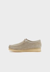 Scarpe in suede beige con punta rotonda, lacci in pelle e suola in gomma di un leggero color nocciola, caratterizzate da una texture liscia e un design minimalista.
